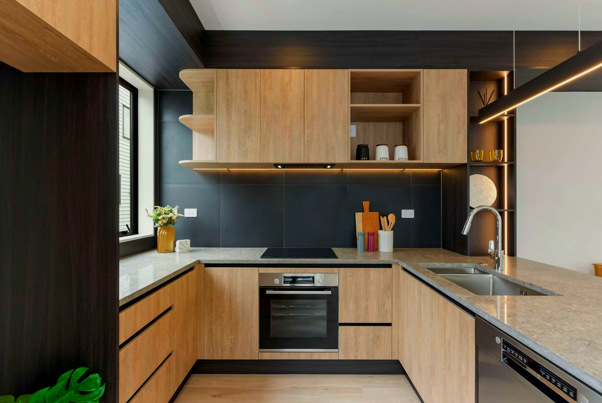 Modern kitchen with wood cabinets, black backsplash, and stainless steel appliances.