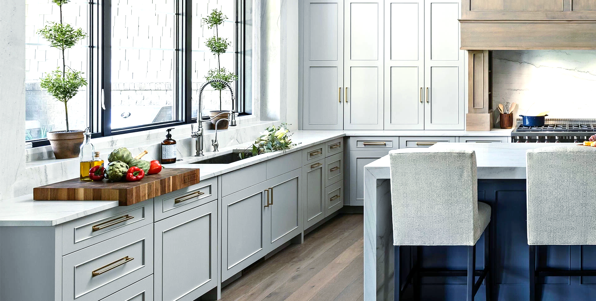 A kitchen with white cabinets, a wooden cutting board, a sink, and a large island.