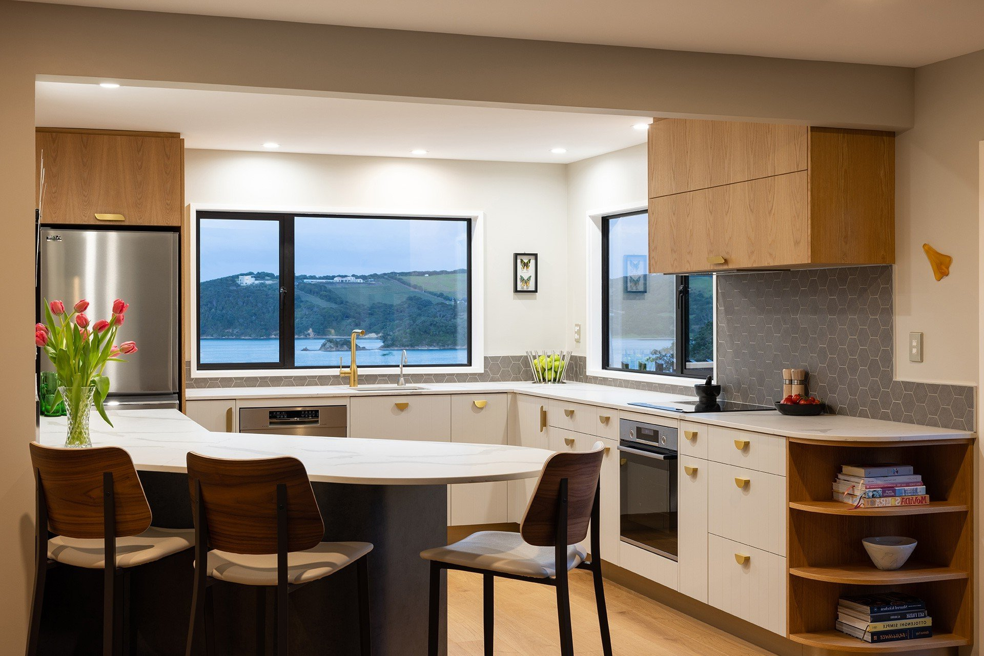 Modern kitchen with light wood cabinets, white counters, and a view of the water.