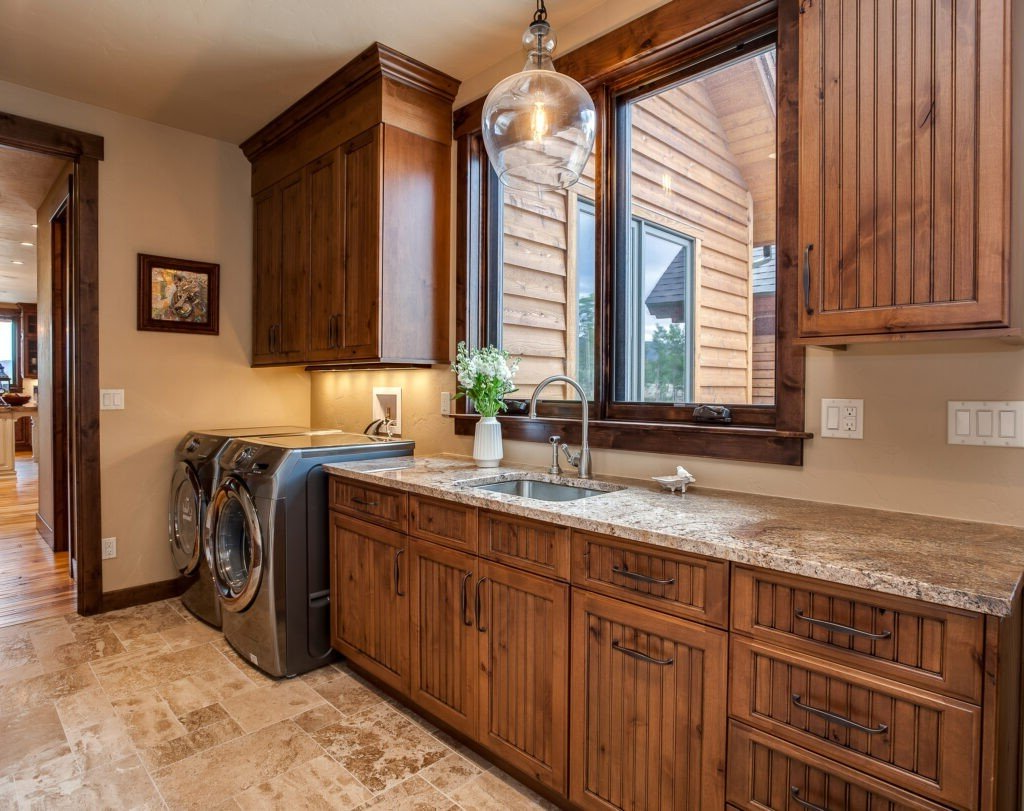 Laundry room with wood cabinets, a sink, washer and dryer, and a window.