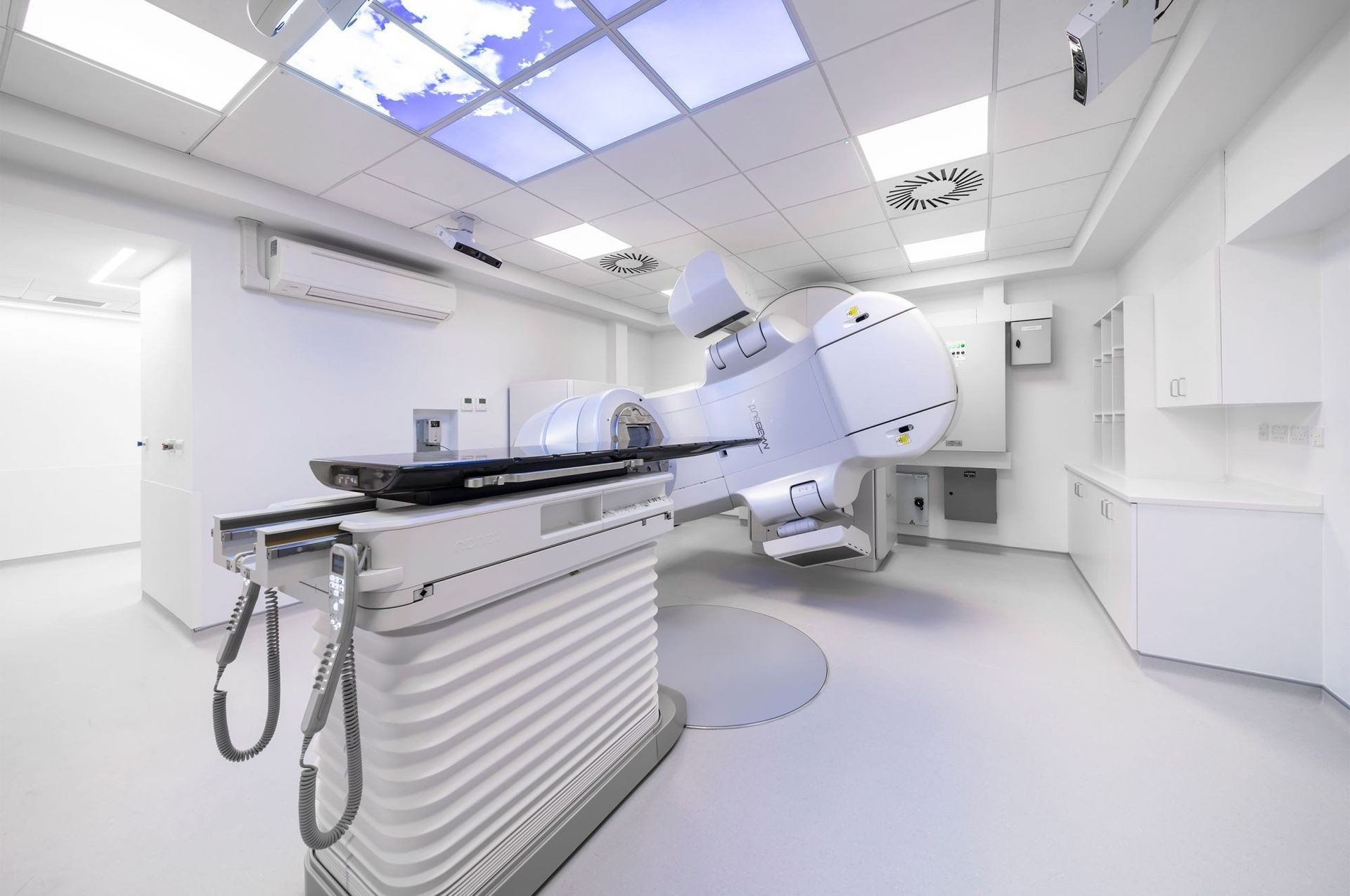 Modern medical imaging room with a CT scanner and examination table, bright white interior.