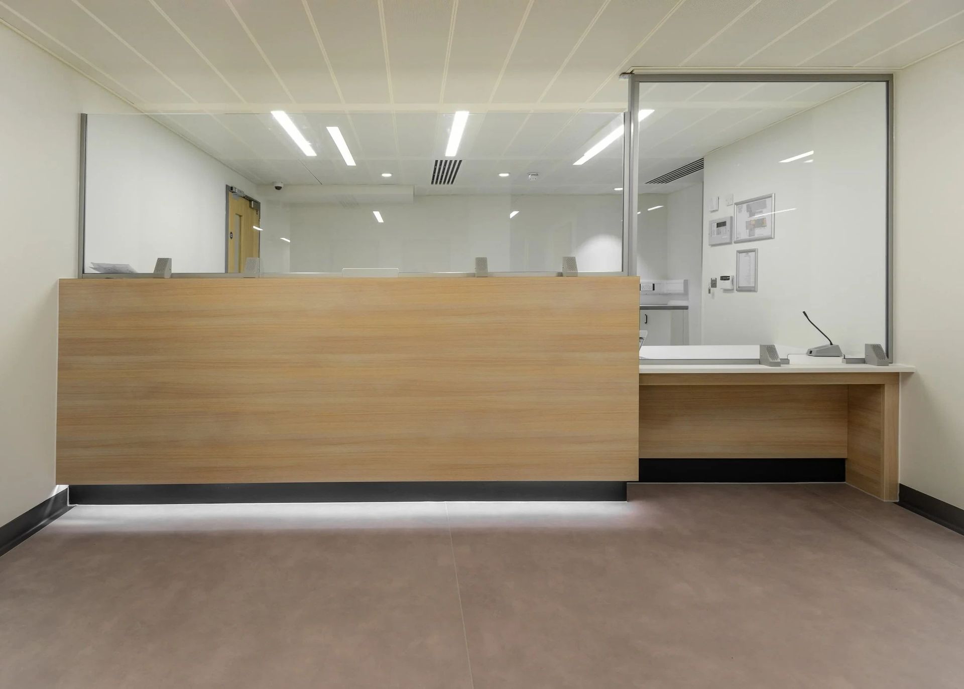 Empty modern office reception desk with wood paneling and glass partition.