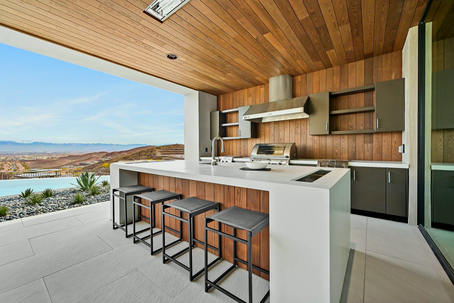 A kitchen with a large island and stools and a view of the mountains.