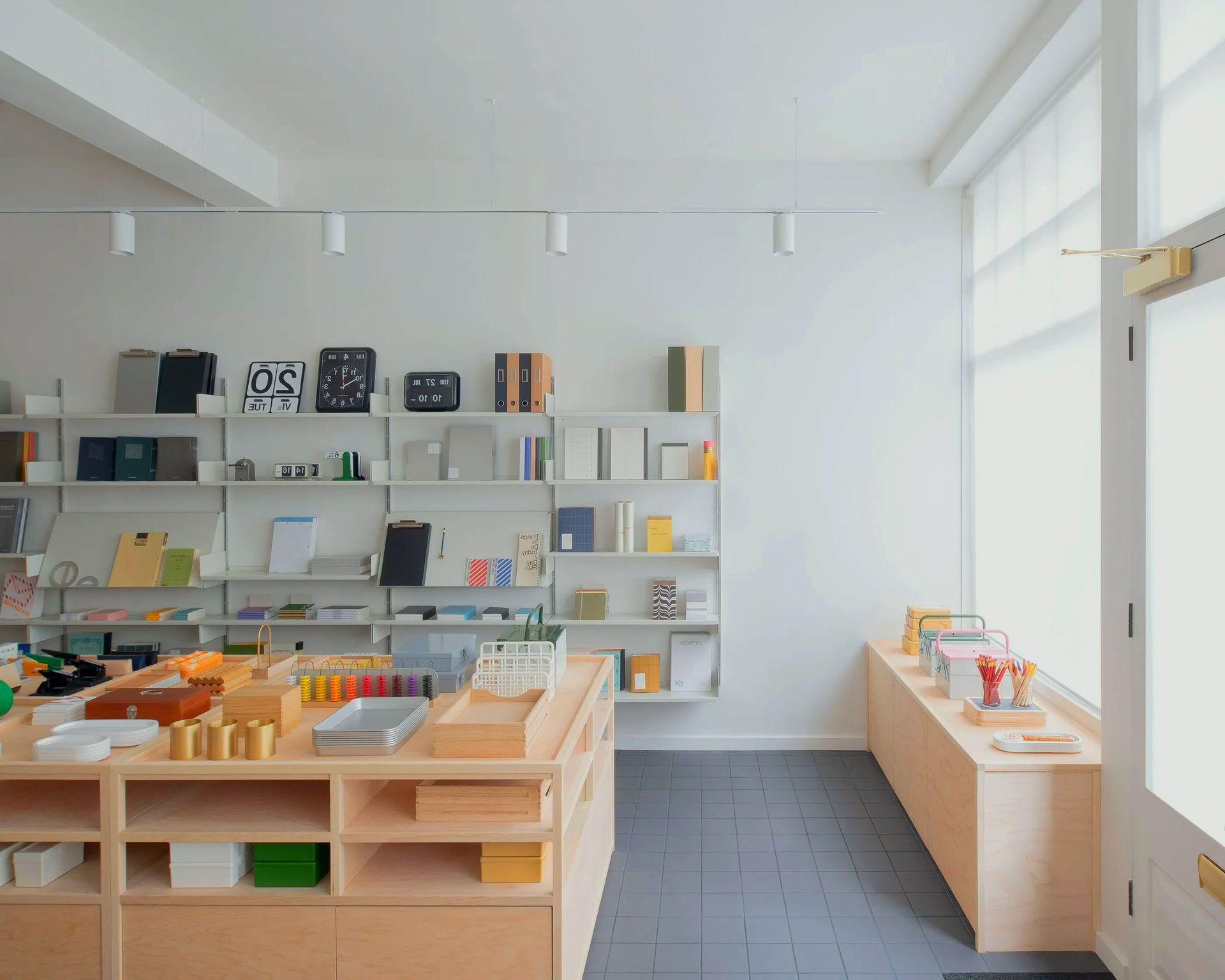 Bright minimalist shop interior with shelves, display tables, and small items on a gray floor.