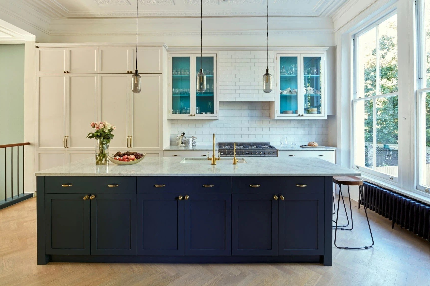 A light-filled kitchen with black and white cabinets, and hanging lights