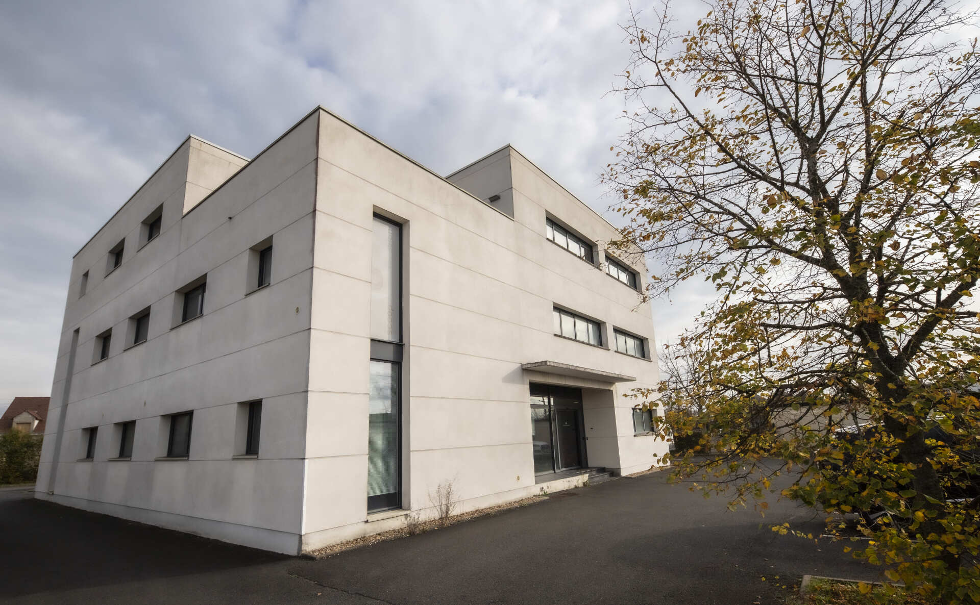 Immeuble moderne blanc de trois étages avec de petites fenêtres rectangulaires.