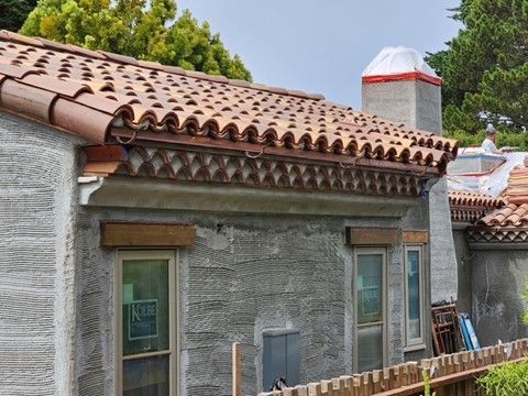 House with clay tile roof and stucco siding, undergoing construction.