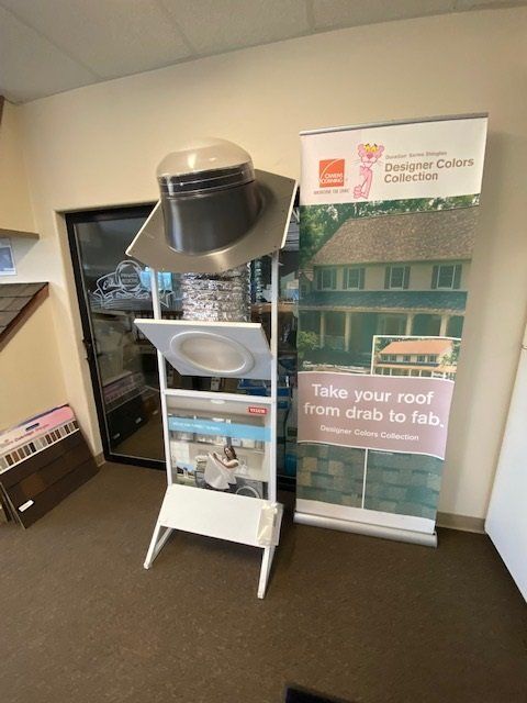 Display stand with roofing materials, a banner, and door in a store.