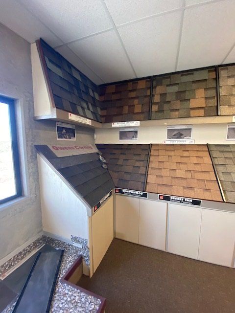 Roofing shingle samples displayed in a showroom. Various colors and textures.
