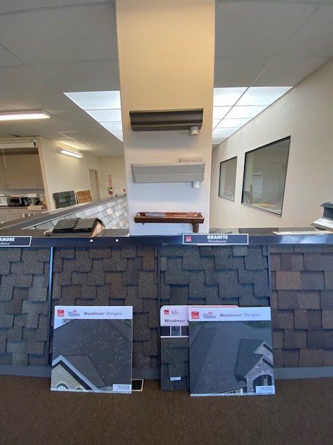 Roofing samples on display in a showroom, showcasing various shingle colors and textures.
