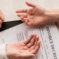 Two hands on a divorce decree with wedding rings, signaling separation