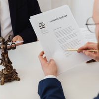 Hands exchanging a divorce decree document at a desk, with a gavel in the foreground.