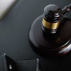 Close-up of a judge’s gavel on a dark desk with a blurred law book in the foreground