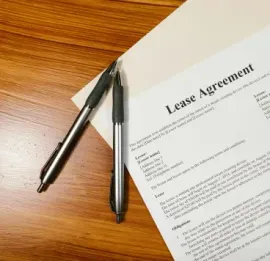 Pens resting on a signed lease agreement on a wooden desk