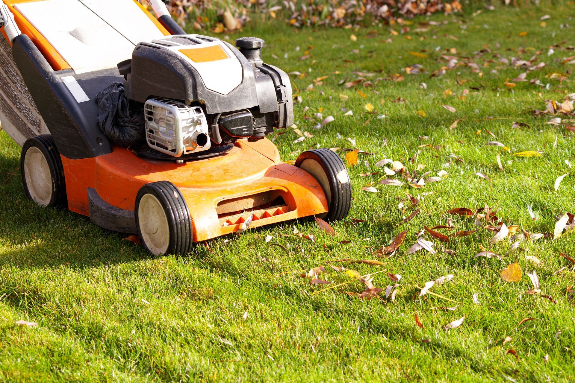 Orange lawnmower cutting grass on a sunny day.