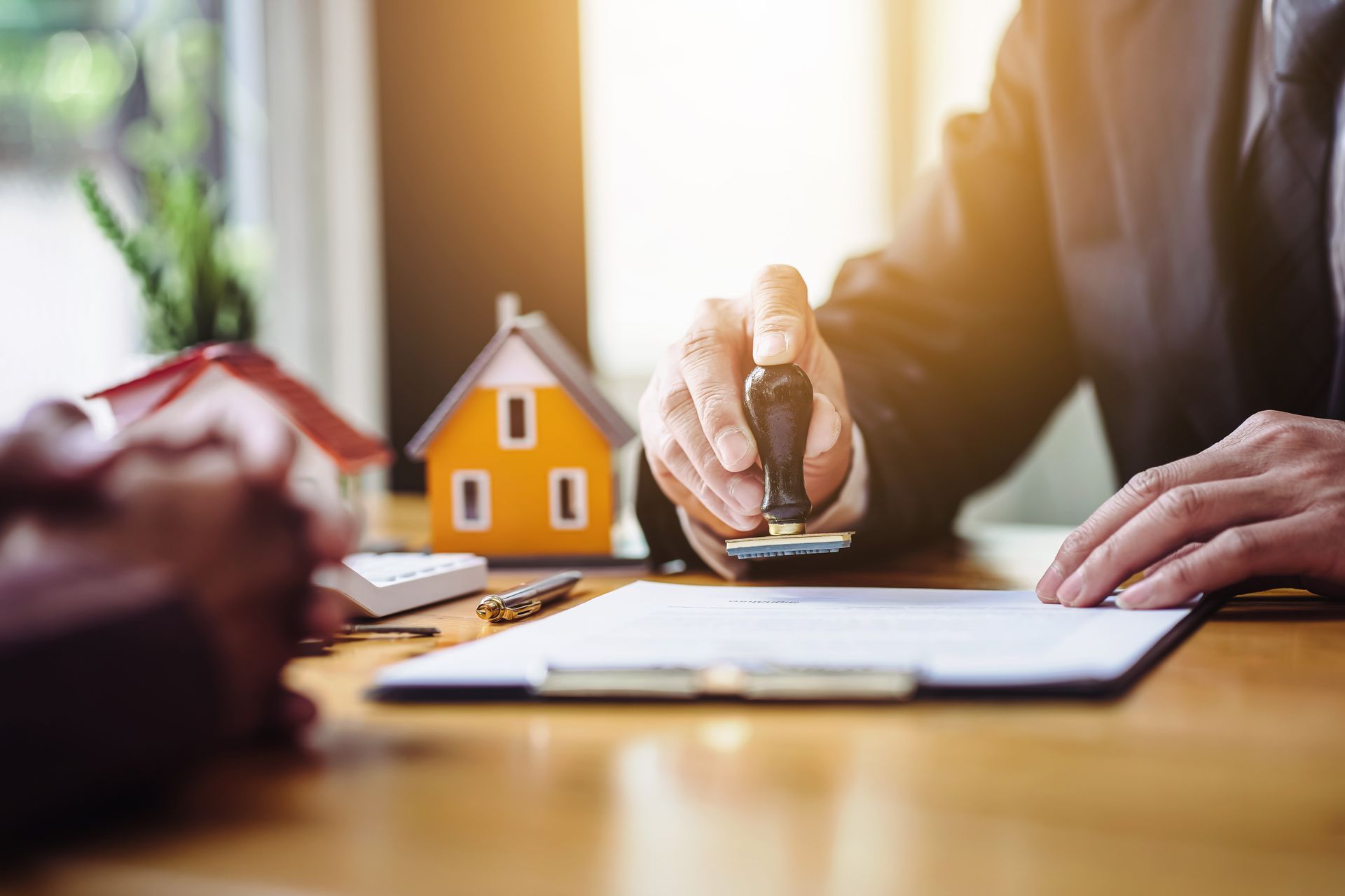 Close-up of a conveyancing solicitor's hand stamping approved property purchase documents.