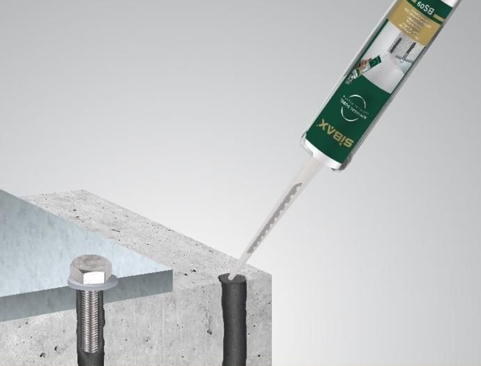 A tube of sealant is being applied to a concrete surface