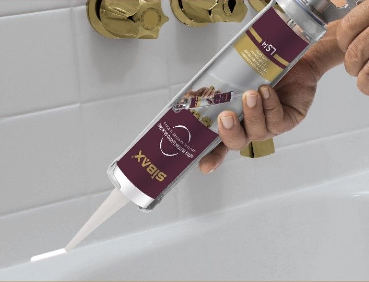 A person is holding a tube of sibax silicone sealant