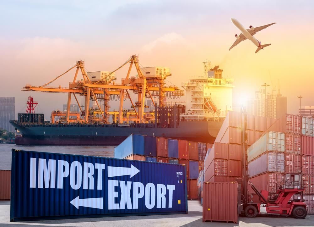 A plane is flying over a port with a sign that says import and export.