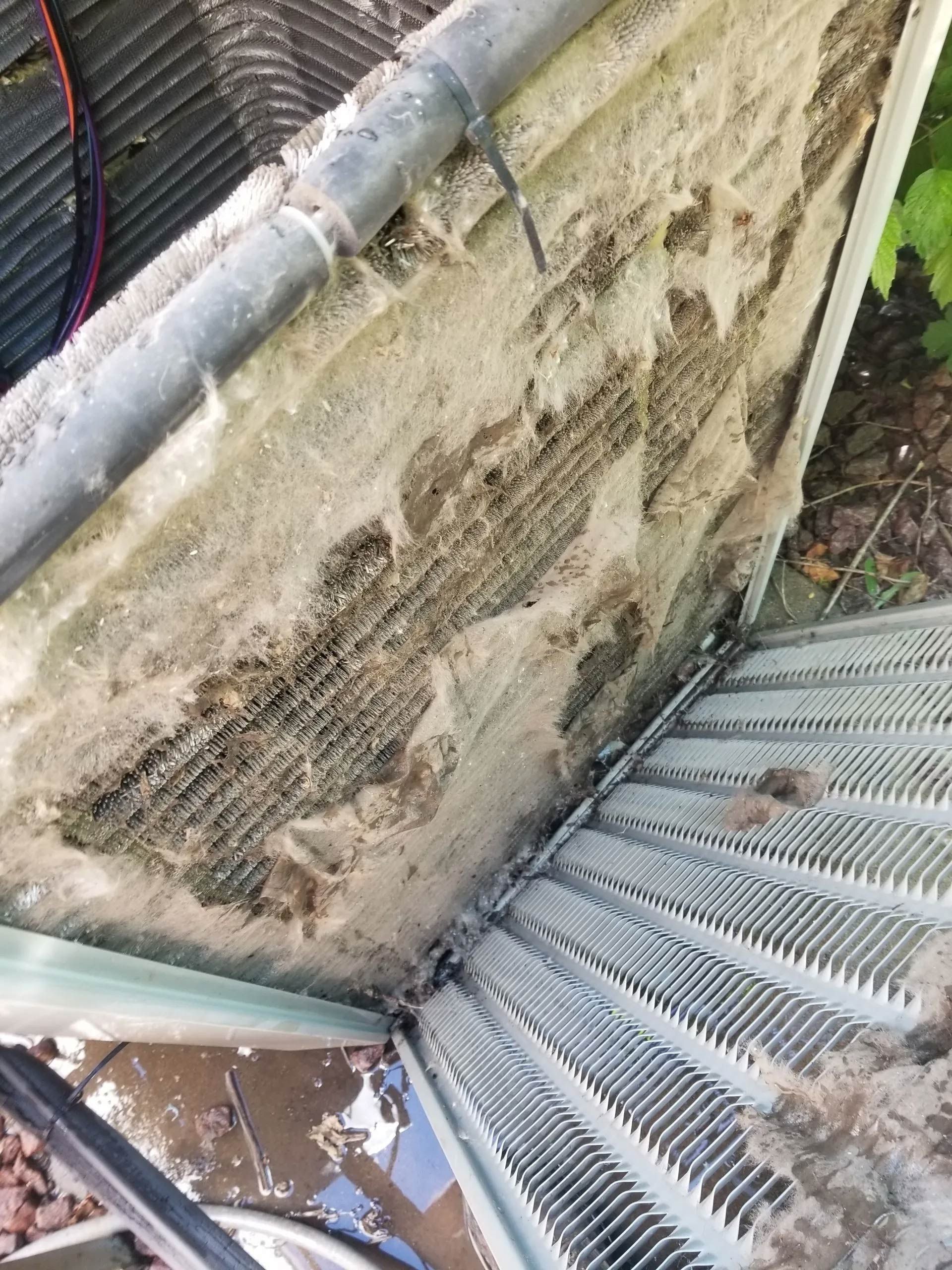 Rusty metal vent and debris beside a weathered wall and corrugated roofing outdoors