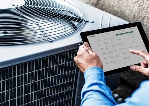 Technician using a tablet to inspect an outdoor air conditioning unit