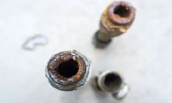 Close-up of three corroded metal nuts on a white surface with one blurred in the background