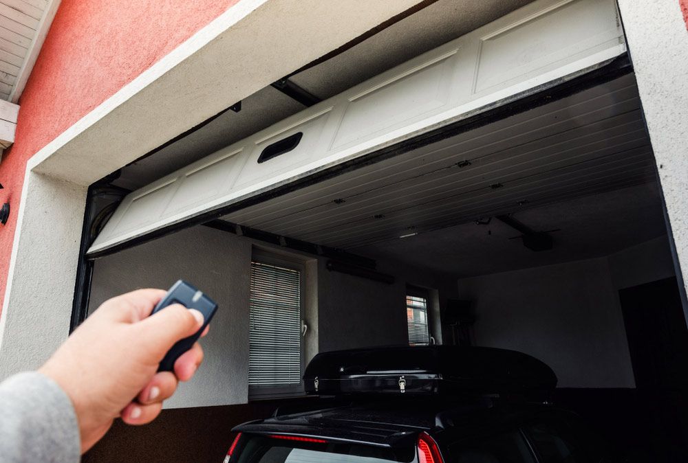 A Person is Using a Remote Control to Open a Garage Door — Mackay Garage Doors in Andergrove, QLD