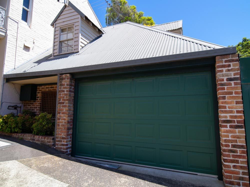A House With a Green Garage Door and a Brick Wall — Mackay Garage Doors in Andergrove, QLD