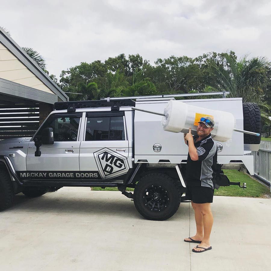 A Man is Standing in Front of a Truck That Says Mg on the Side — Mackay Garage Doors in Andergrove, QLD
