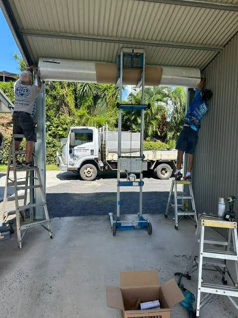 A Group of Men Are Working on a Garage Door — Mackay Garage Doors in Andergrove, QLD