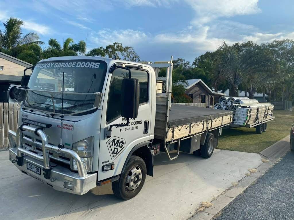 A White Truck With a Flat Bed is Parked in a Driveway — Mackay Garage Doors in Andergrove, QLD