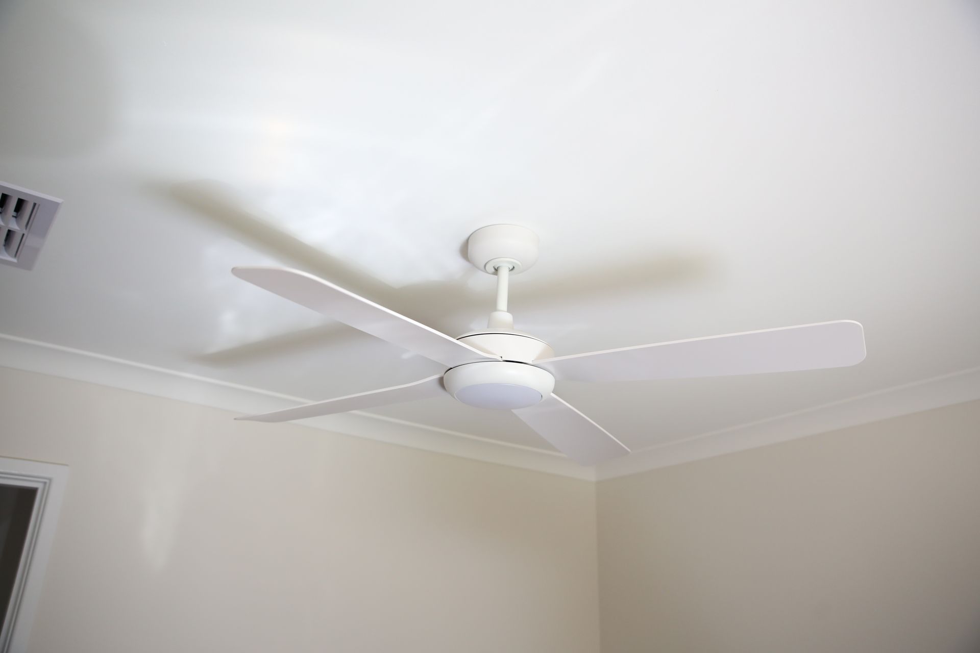 White ceiling fan spinning in a beige room with crown molding