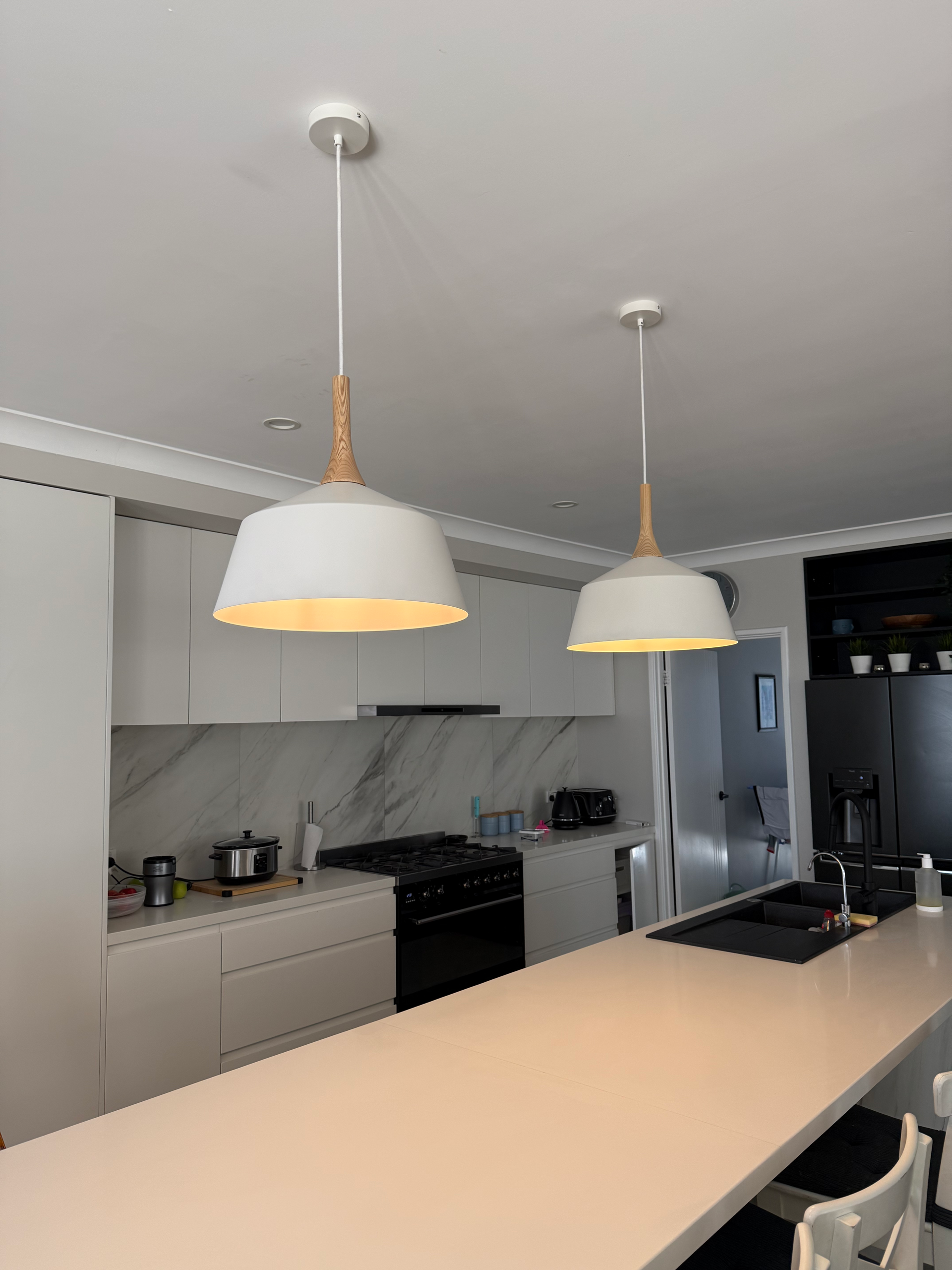 Modern kitchen with beige island, white cabinets, stainless steel appliances, and two pendant lights