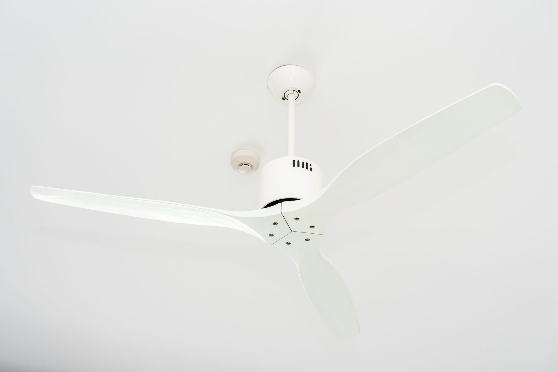 White ceiling fan with three blades mounted on a plain white ceiling