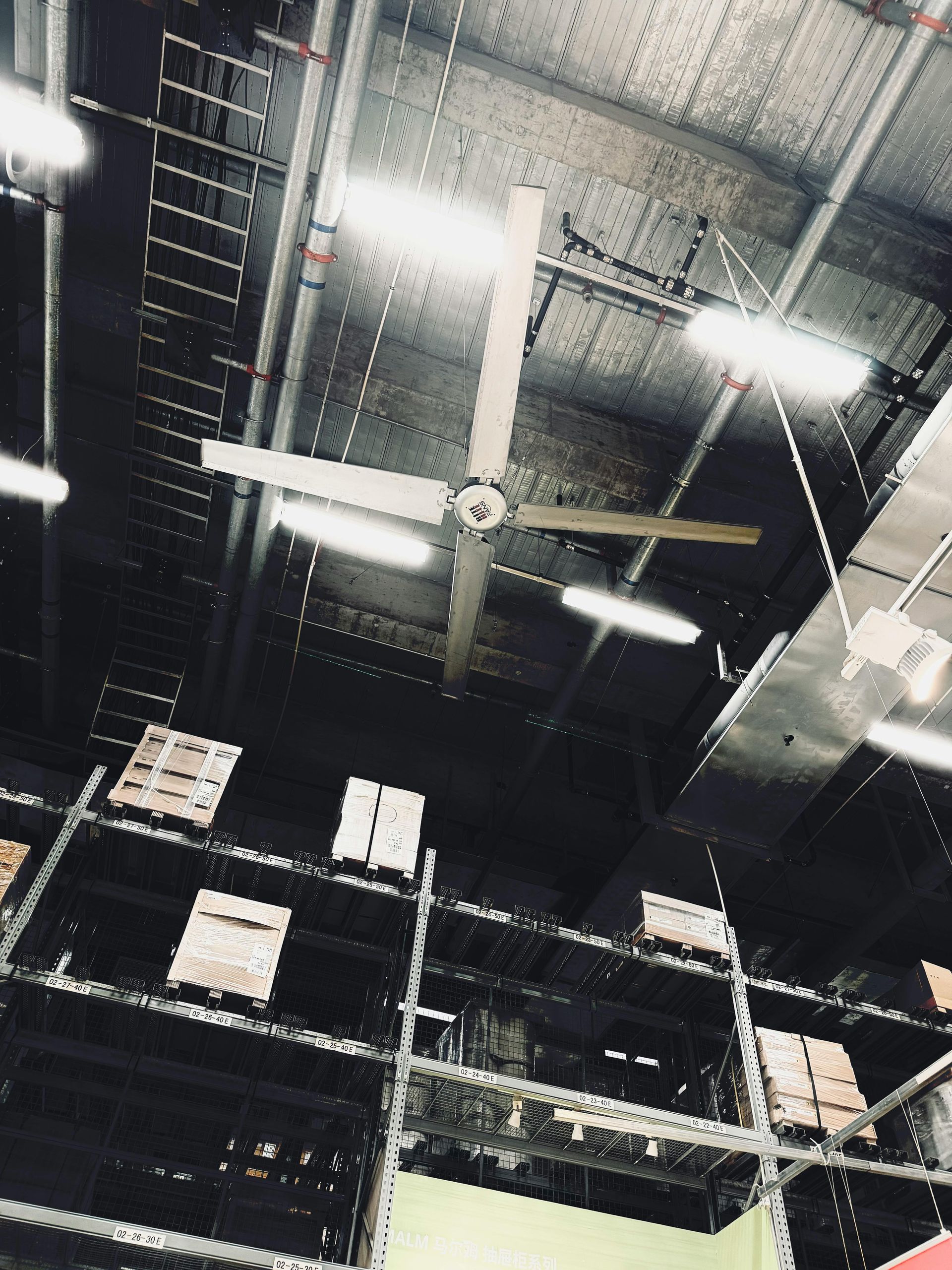Industrial ceiling with fluorescent lights, exposed beams, and hanging cables in a dim warehouse interior