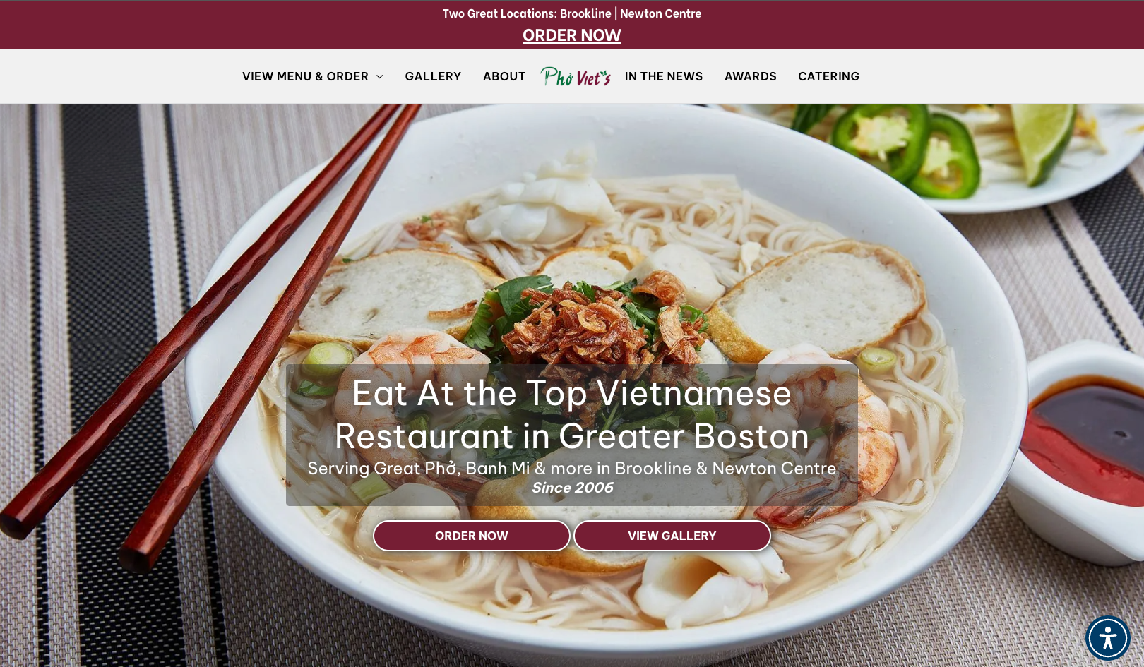 Bowl of Vietnamese pho with chopsticks and restaurant banner.