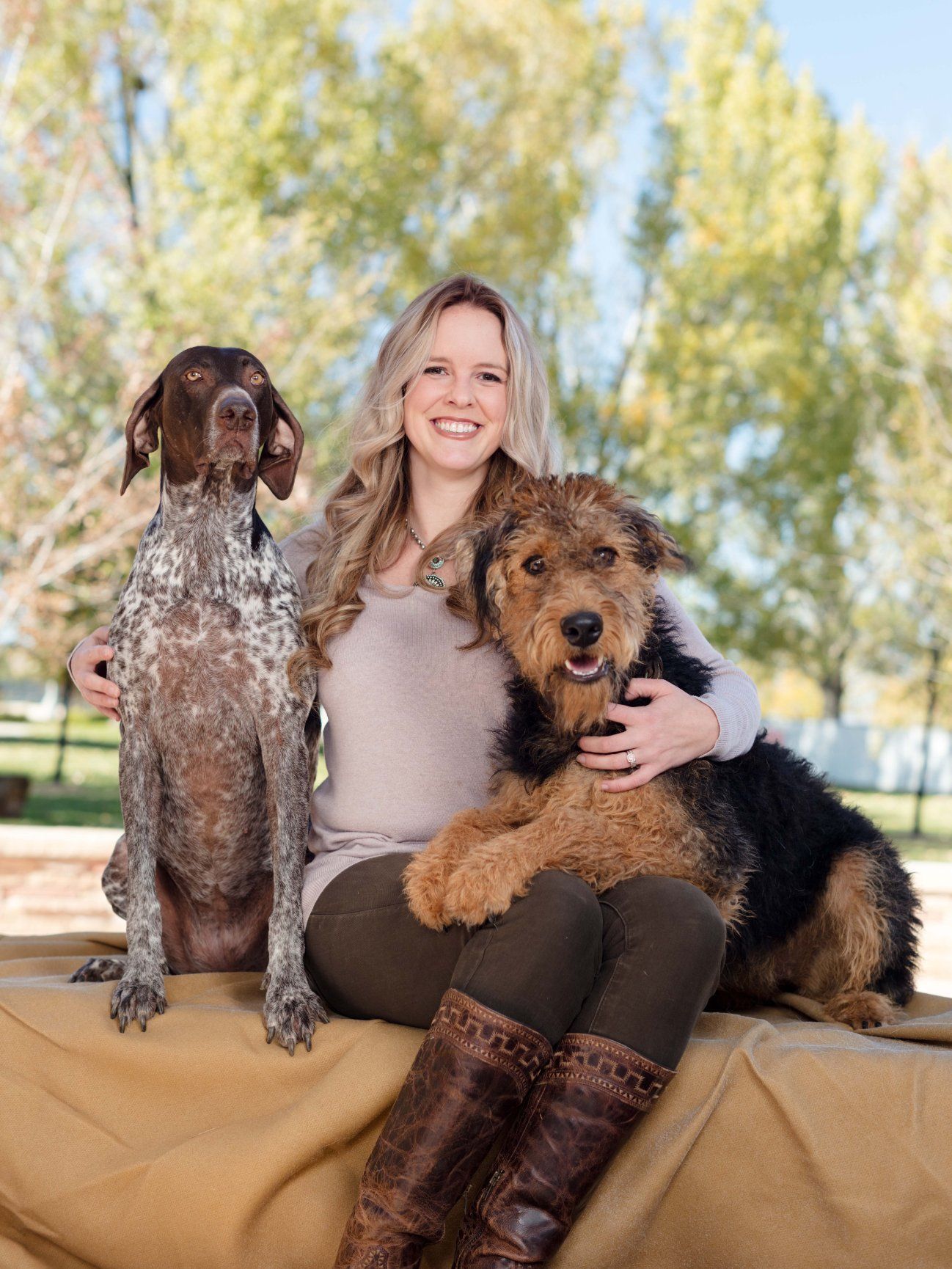 A woman in a white coat is kneeling down next to a brown dog.
