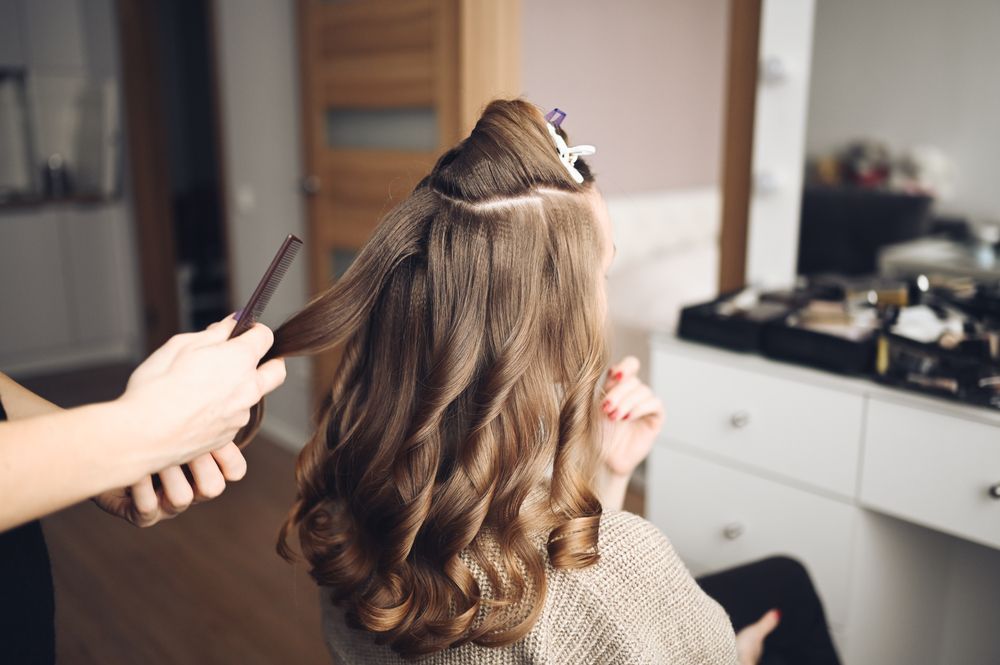 A woman is getting her hair done by a hairdresser in a salon.