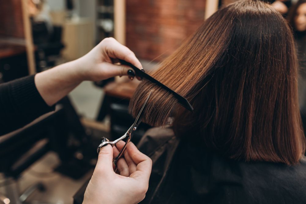 A woman is getting her hair cut by a hairdresser in a salon.