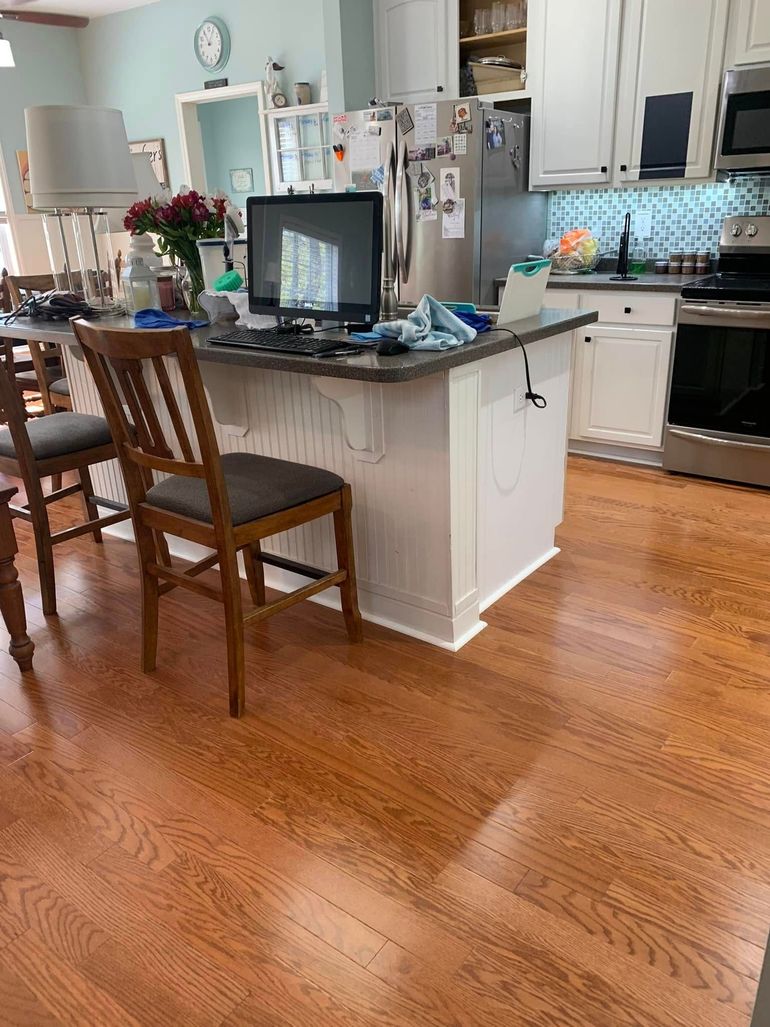 Kitchen with island, two wooden chairs, hardwood floors, and a laptop on the counter.