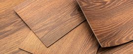 Wooden floor sample boards with brown grain textures arranged on a wood surface