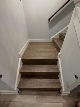 Narrow indoor staircase with wood steps, white walls, and a small landing at the top