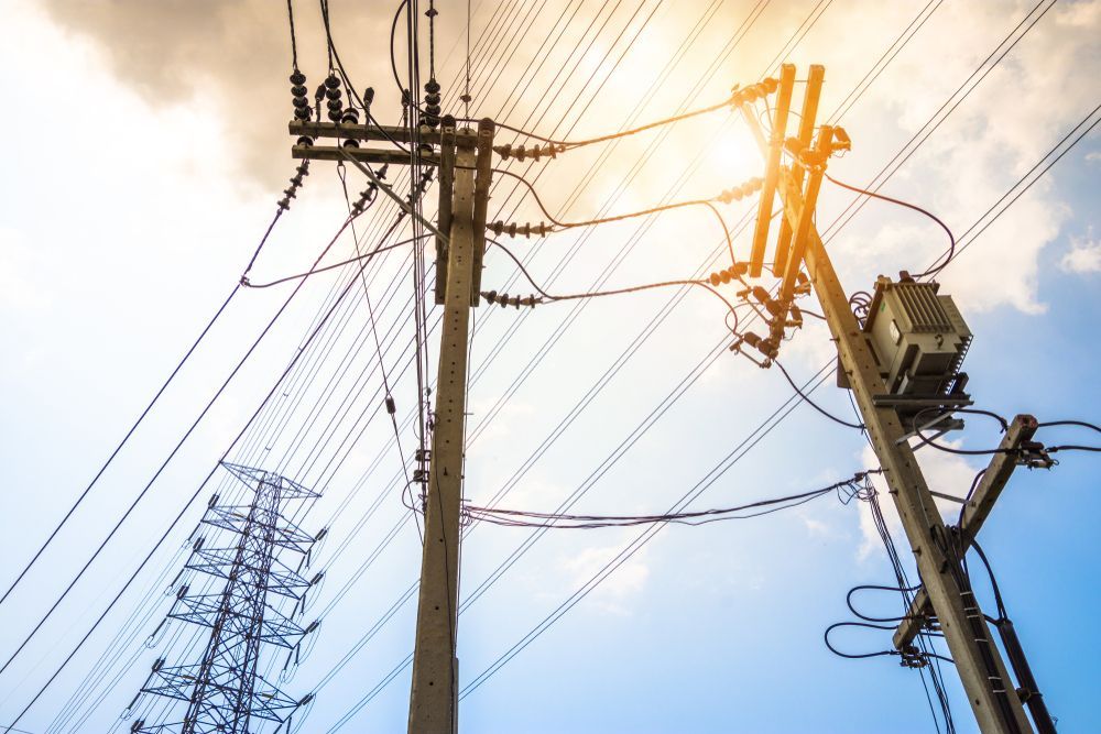 Power Lines, Poles, and Transformer Against a Blue Sky With Sunlight — Holders Electrical In Tenterfield, NSW