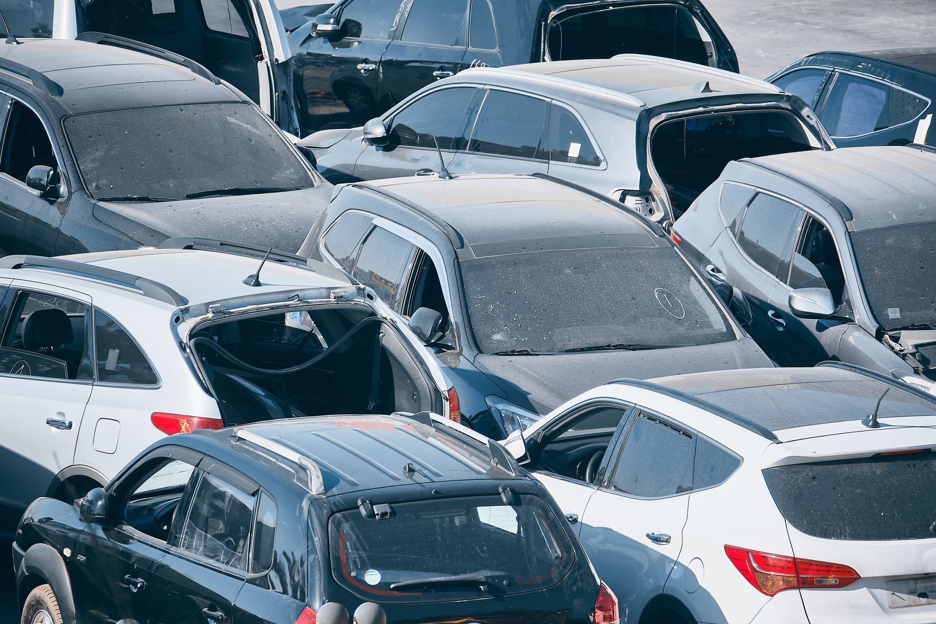 Crowded parking lot filled with mostly white and gray cars viewed from above