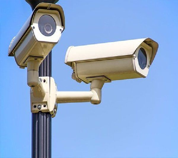 Two security cameras on a pole with a blue sky in the background