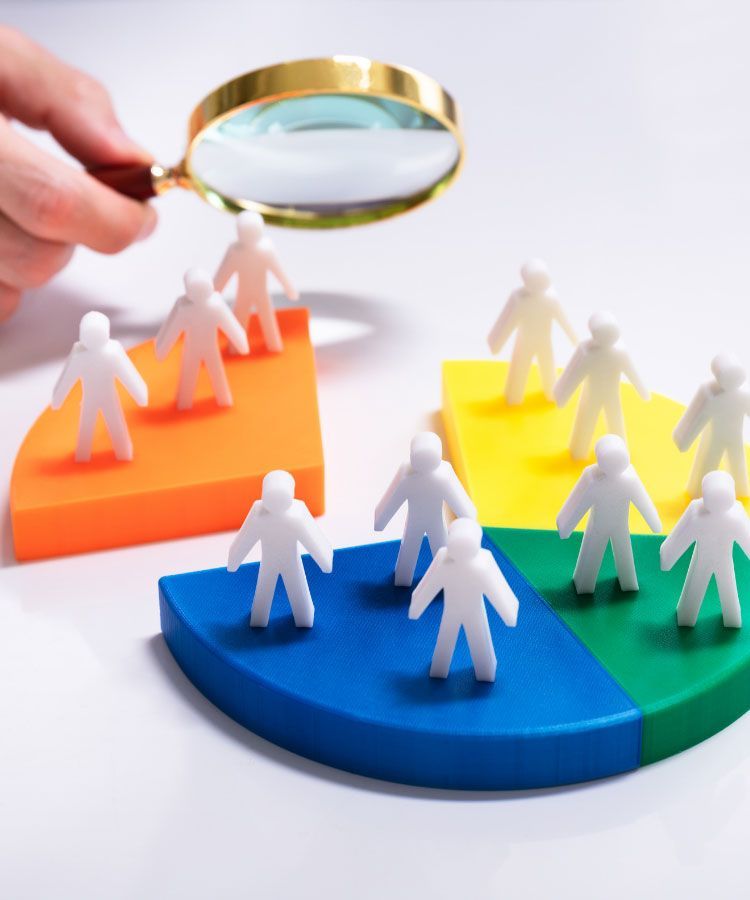 Magnifying glass inspecting paper figures on a multicolored pie chart