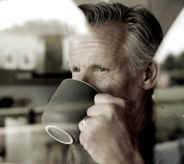 A man drinking a cup of coffee with a ring on his finger