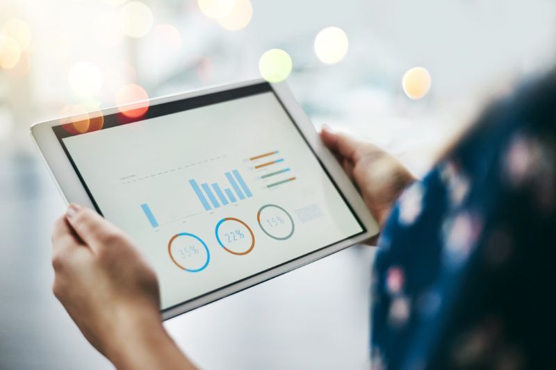 Person holding a tablet with analytics charts and graphs on the screen