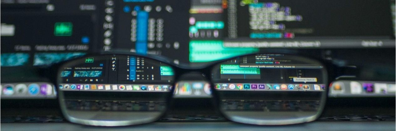 Glasses in front of a laptop, with blurred screen, showing a computer program interface.