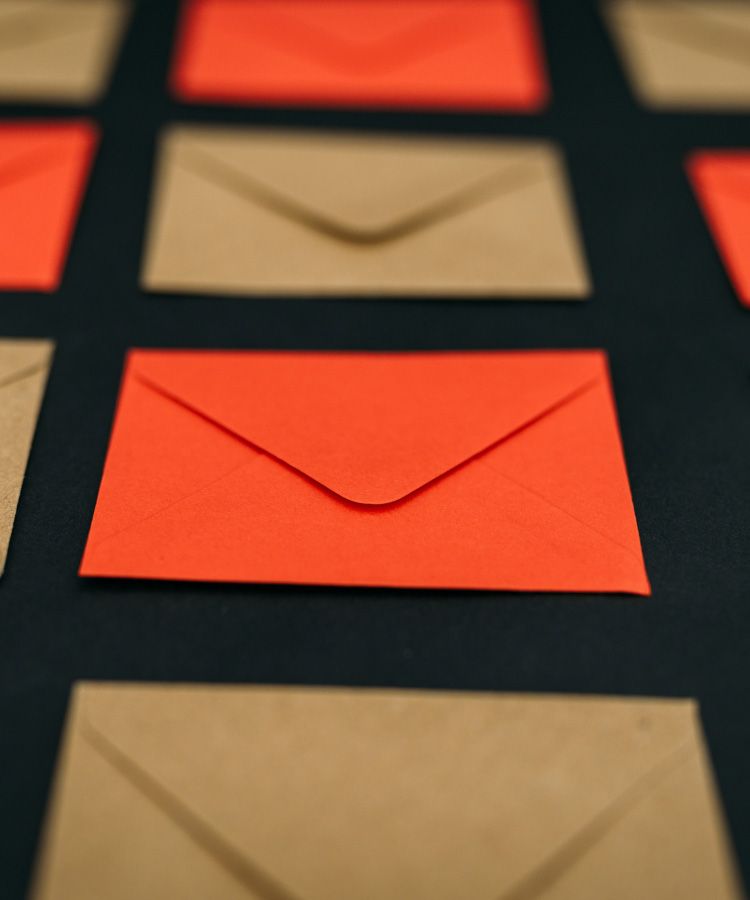 Red and tan envelopes arranged on a dark surface, with one red envelope in focus.